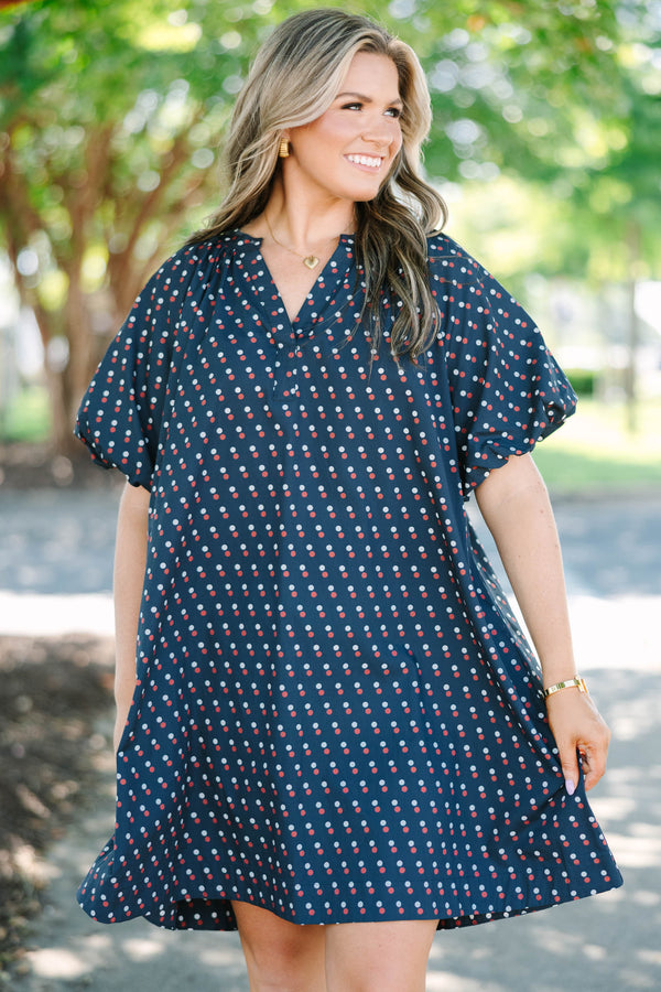 Plus size navy shift dress with red and white polka dots, featuring a flowy fit and V-neckline.