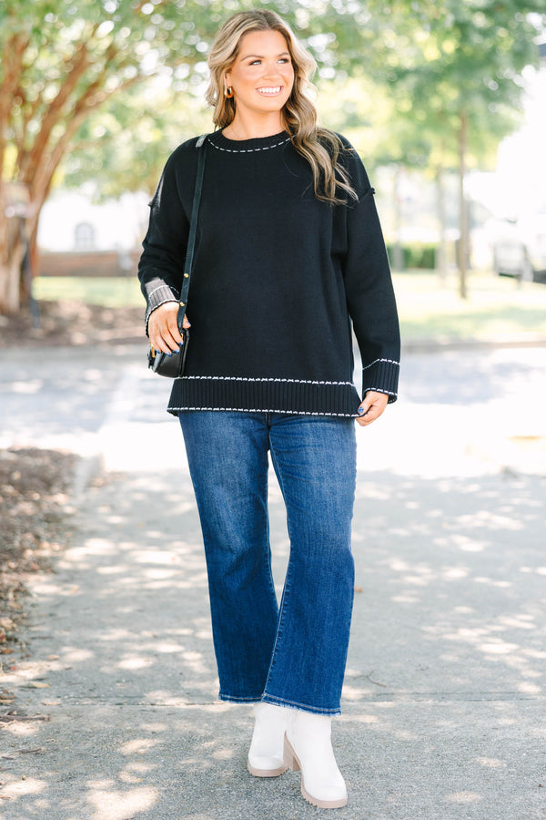 Plus size black knit sweater with white contrast stitching on the neckline, cuffs, and hem.