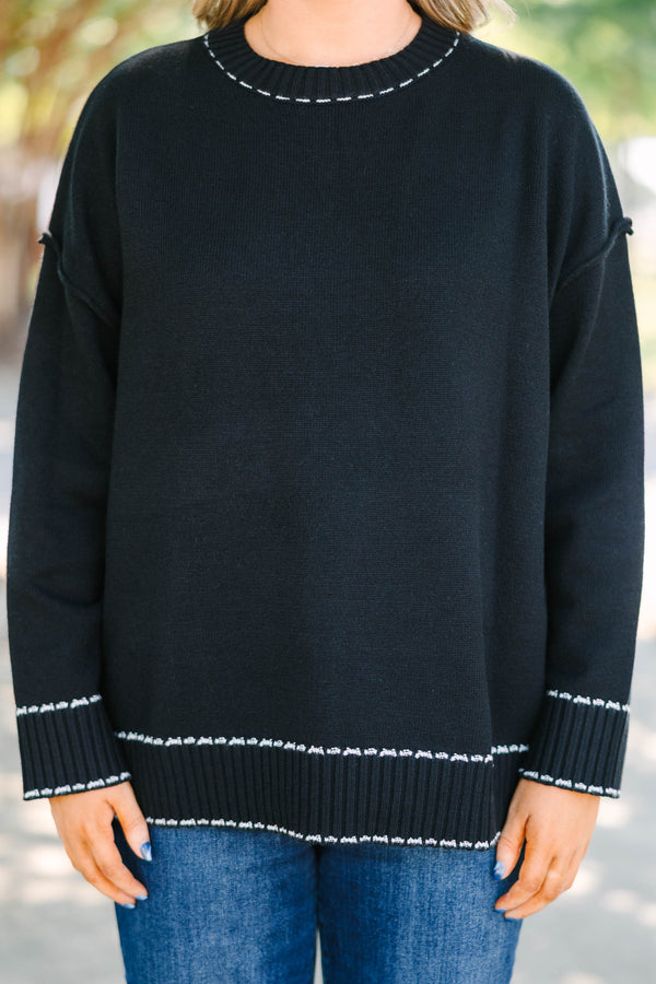 Plus size black knit sweater with white contrast stitching on the neckline, cuffs, and hem.