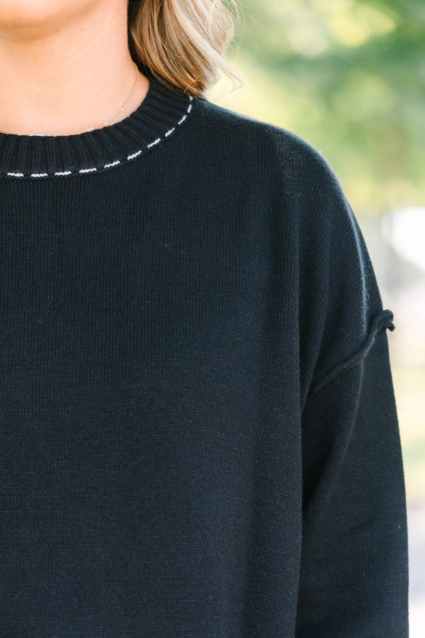 Plus size black knit sweater with white contrast stitching on the neckline, cuffs, and hem.