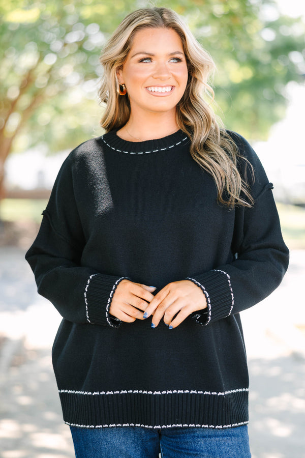 Plus size black knit sweater with white contrast stitching on the neckline, cuffs, and hem.