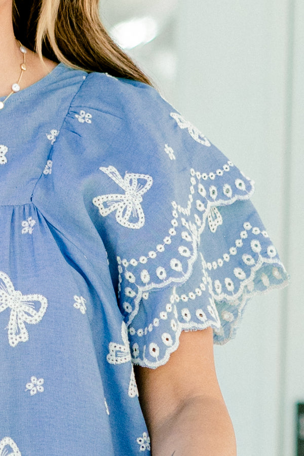 Chic Soul plus size clothing, denim top with flutter sleeves and white embroidered bows and flowers details throughout the top 
