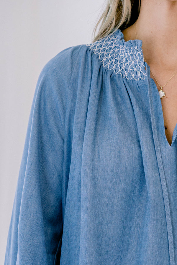 Chic soul plus size clothing, long sleeve flowy denim blouse with white stitching detailing around the collar and cuff of the sleeves, with 2 drawstrings at the collar