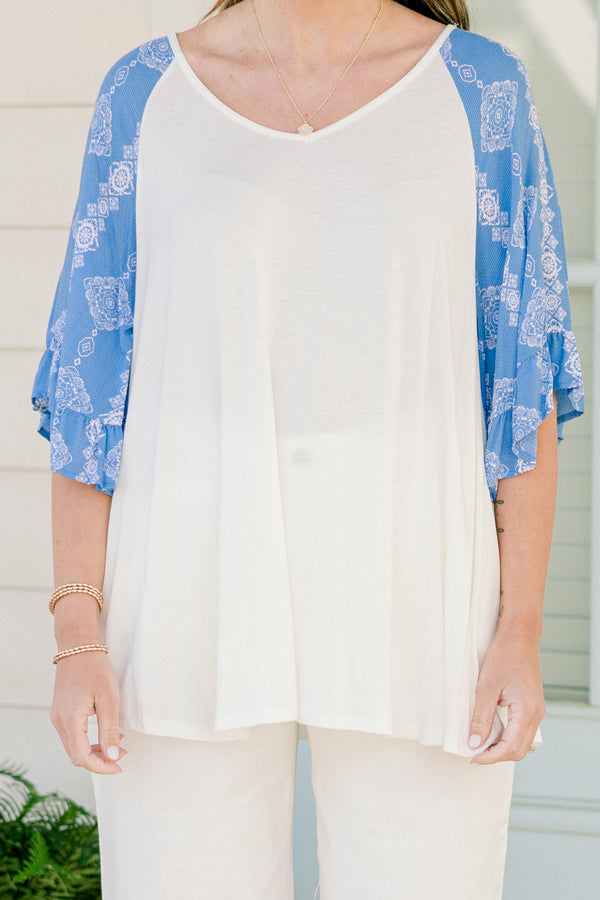 Plus Size white bodice top with blue abstract print raglan sleeves and a scoop neckline.