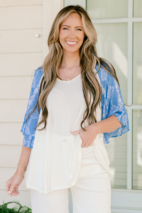 Plus Size white bodice top with blue abstract print raglan sleeves and a scoop neckline.