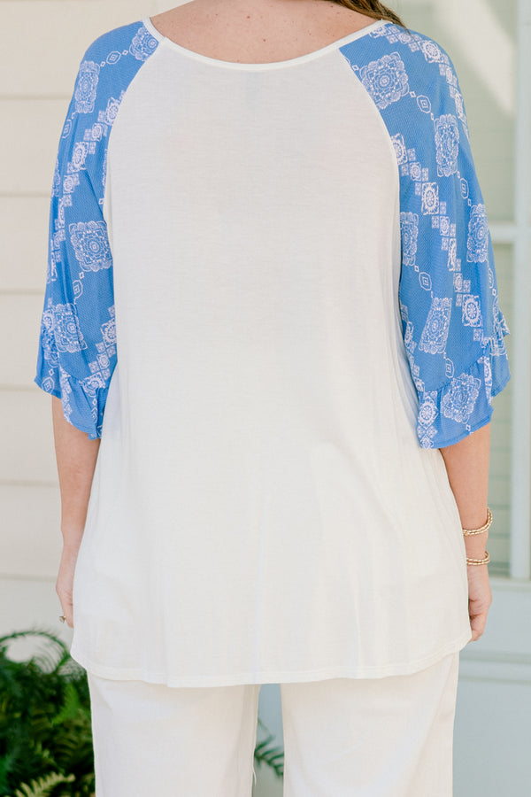Plus Size white bodice top with blue abstract print raglan sleeves and a scoop neckline.