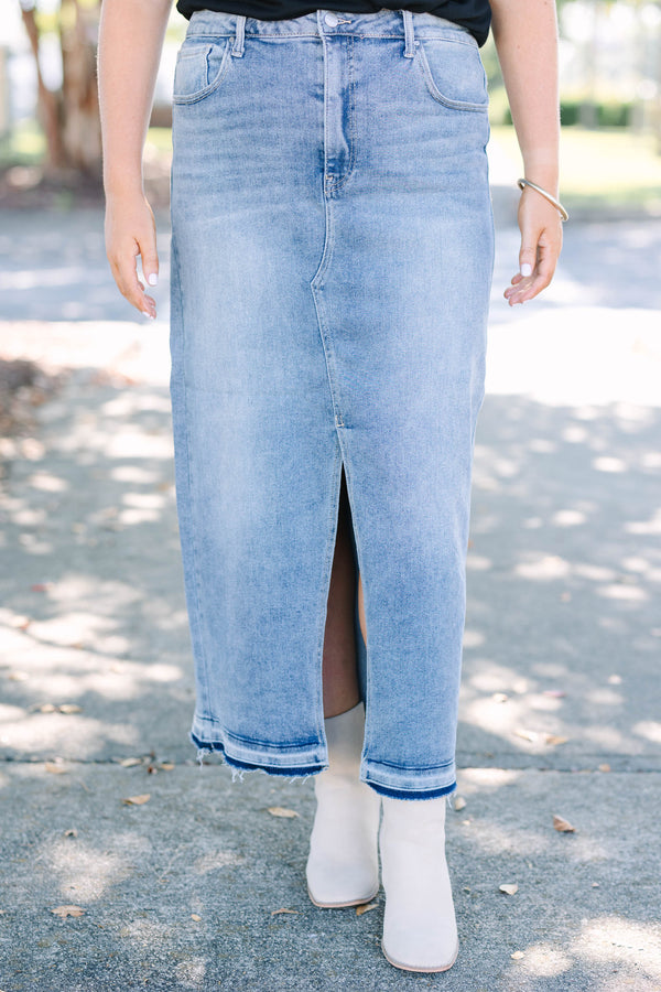 Plus size medium wash denim midi skirt with a front slit and raw hem for a confident, chic look.