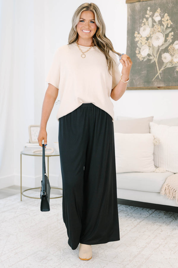 Plus size black flowy palazzo pants with a high-rise elastic waistband and soft ribbed fabric.