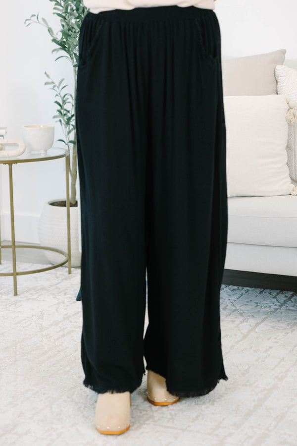 Plus Size black wide-leg pants with an elastic waistband, side pockets, and frayed hem detail.