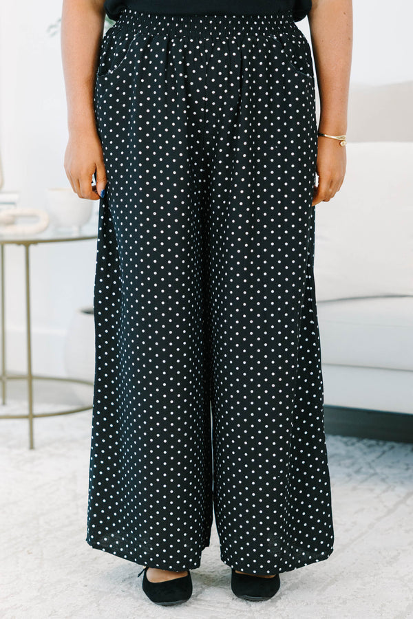 Plus size black wide-leg pants with white polka dots featuring a flowy fit and smocked waist.