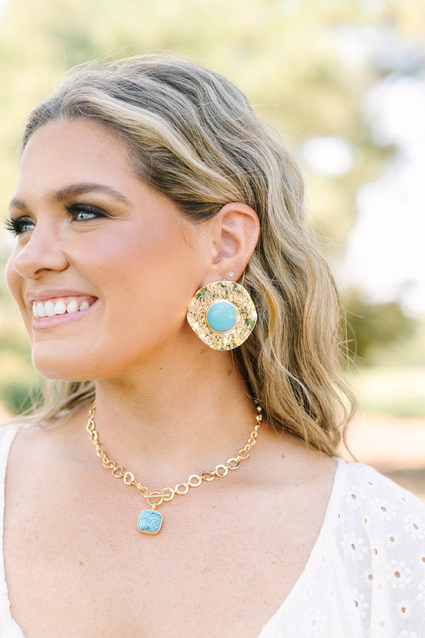 Large hammered gold disc earrings with a round turquoise stone center.