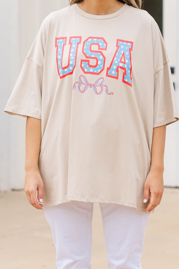 Plus Size light mocha oversized boyfriend tee with a USA star graphic and white pants.