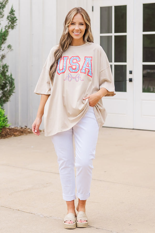Plus Size light mocha oversized boyfriend tee with a USA star graphic and white pants.
