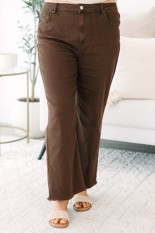 Plus size dark brown wide leg jeans with a raw hem and stretchy cotton fabric.