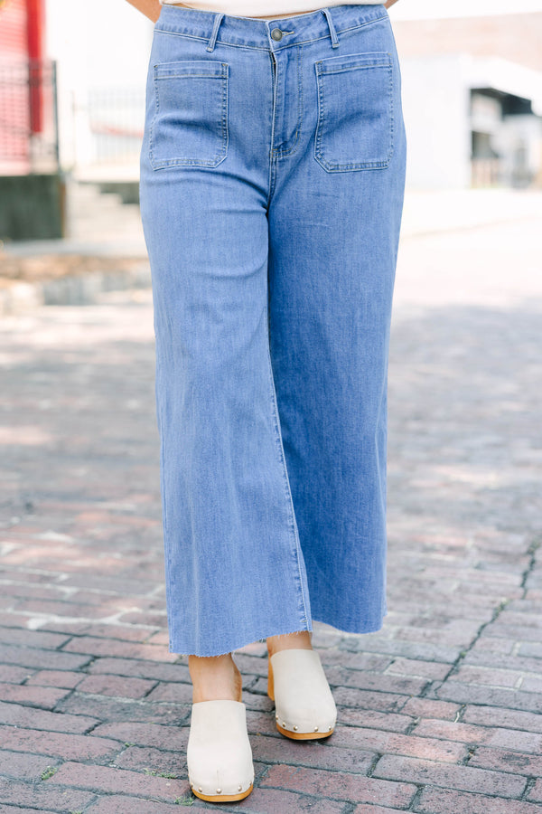 Plus Size medium wash wide leg cropped jeans with front patch pockets and a frayed hemline.