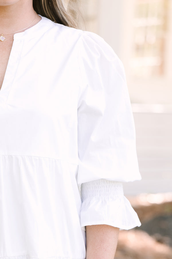 Plus Size white babydoll dress with a split v-neck, smocked cuffs, and mini bell sleeves.

