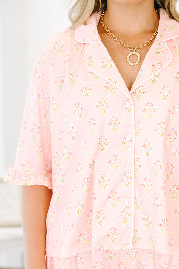 Plus Size pink block print pajama set with short sleeves, button-down top, and ruffled shorts.