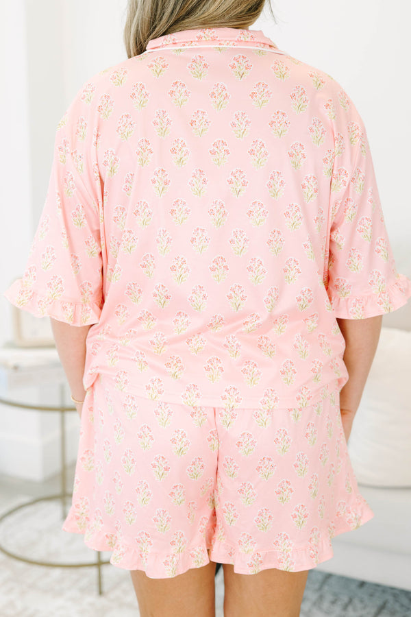 Plus Size pink block print pajama set with short sleeves, button-down top, and ruffled shorts.