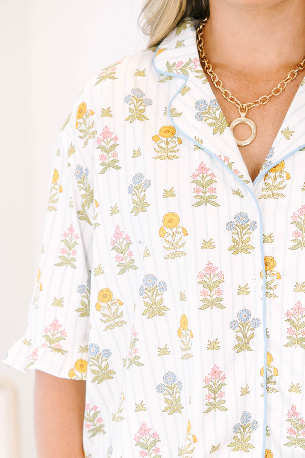 Plus Size white floral pajama set with short sleeves, button-down top, and matching ruffled shorts.