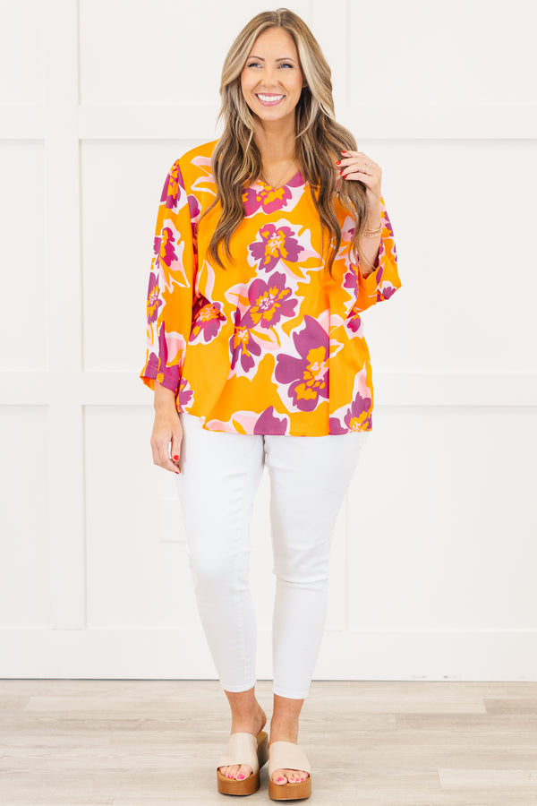 Plus Size orange V-neck top with a bold purple and pink floral print and long sleeves.
