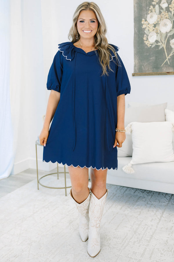Navy blue mini dress features a scalloped collar with white trim and a matching scalloped hemline