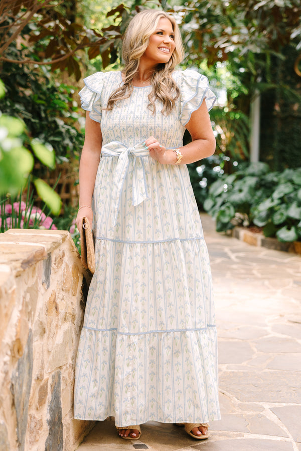 Chic Soul plus size clothing, white tiered dressed with a smocked texture on the chest flutter sleeves a bow that ties around the waist and a blue floral pattern throughout 