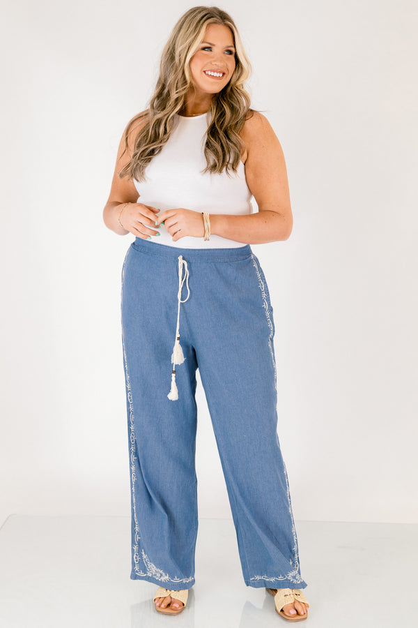 Chic Soul plus size clothing, medium wash denim blue straight leg flowy pants with white embroidery detailing on the ankles and white drawstring tassel tie at the waist