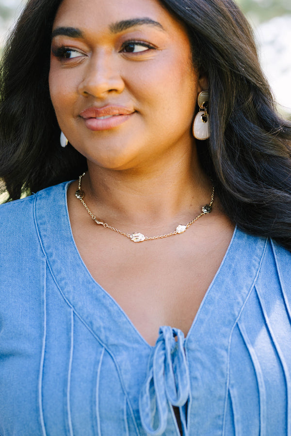 Gold necklace with organic-shaped metal charms.