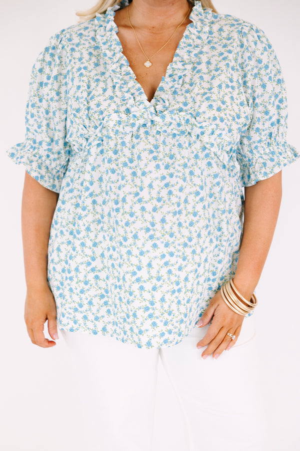 Chic Soul plus size clothing, white top with short sleeves that have a ruffle cuff at the end of the sleeves as well as ruffle detailing going along the v-neckline and under the bust as well as a blue floral pattern 