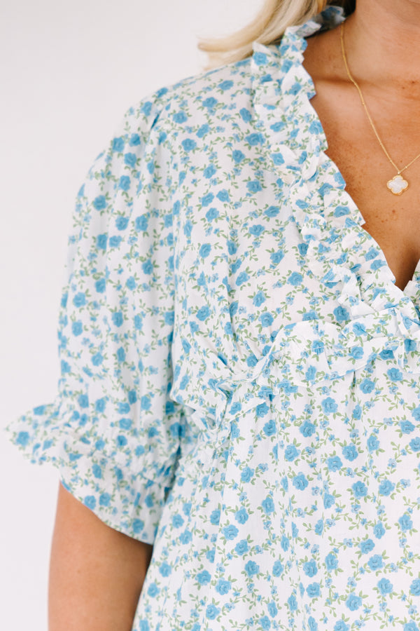 Chic Soul plus size clothing, white top with short sleeves that have a ruffle cuff at the end of the sleeves as well as ruffle detailing going along the v-neckline and under the bust as well as a blue floral pattern 
