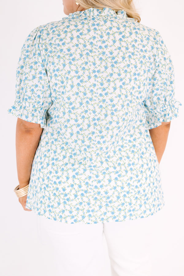 Chic Soul plus size clothing, white top with short sleeves that have a ruffle cuff at the end of the sleeves as well as ruffle detailing going along the v-neckline and under the bust as well as a blue floral pattern 