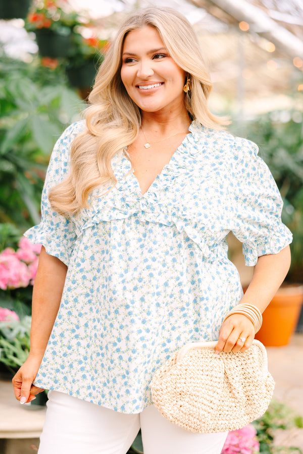 Chic Soul plus size clothing, white top with short sleeves that have a ruffle cuff at the end of the sleeves as well as ruffle detailing going along the v-neckline and under the bust as well as a blue floral pattern 
