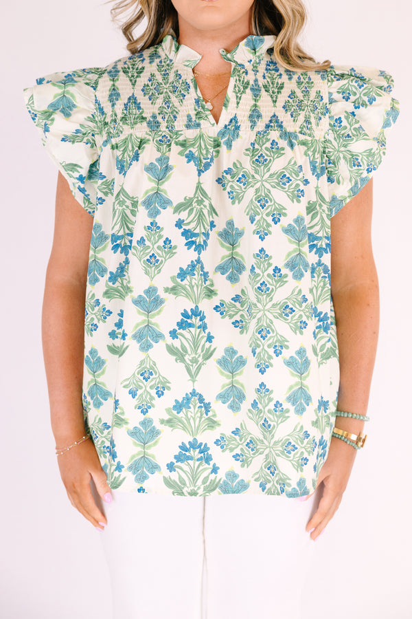 Chic Soul plus size clothing, white top with flutter sleeves and a smocked texture on the shoulders as well as a slight v-neckline and a blue and green floral pattern throughout 