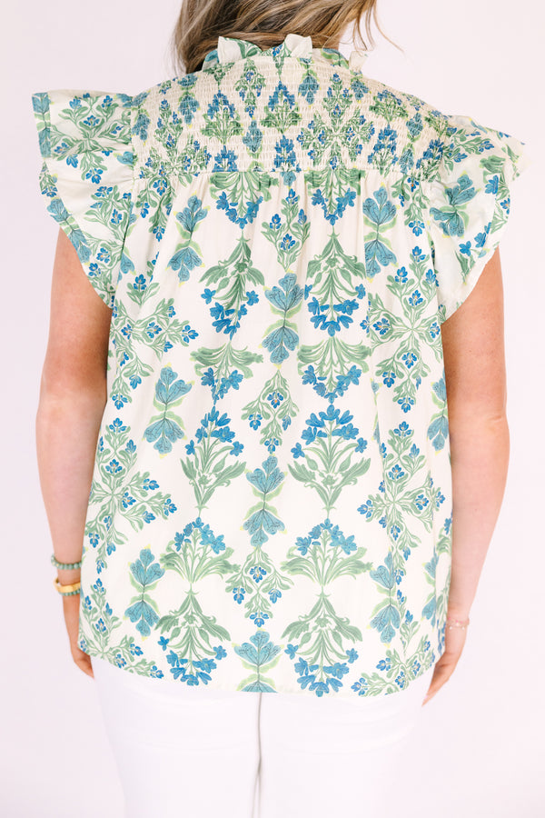 Chic Soul plus size clothing, white top with flutter sleeves and a smocked texture on the shoulders as well as a slight v-neckline and a blue and green floral pattern throughout 