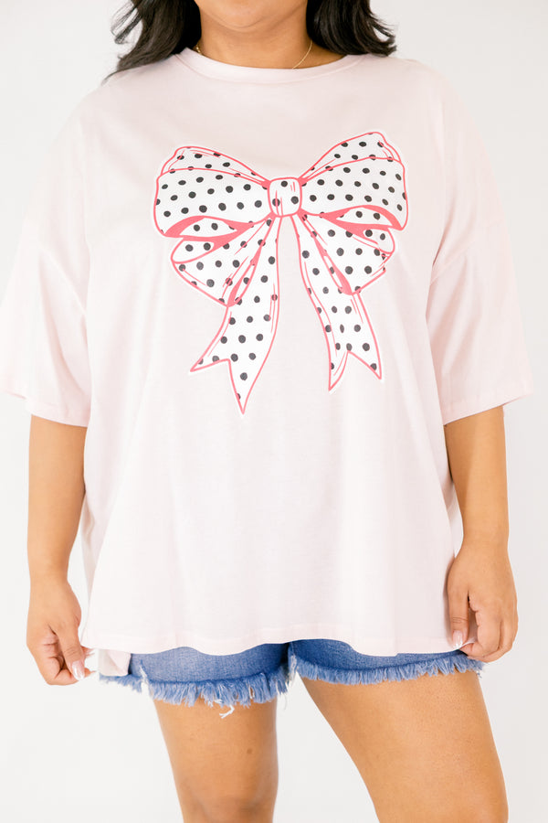 Chic Soul plus size clothing, Cream pink short sleeve graphic tee featuring a white bow graphic centered on the chest, filled with black polka dots and outlined in a darker pink 
