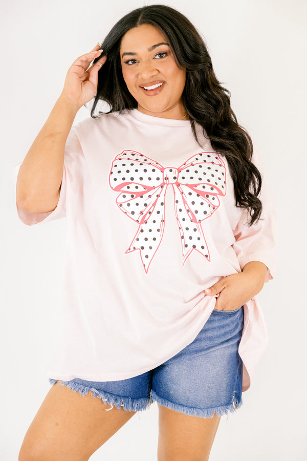 Chic Soul plus size clothing, Cream pink short sleeve graphic tee featuring a white bow graphic centered on the chest, filled with black polka dots and outlined in a darker pink 
