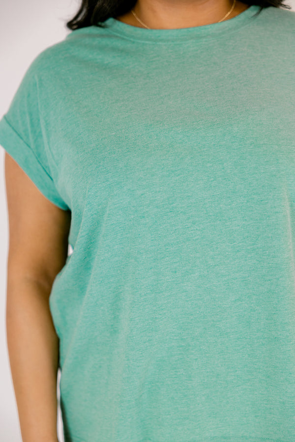 Plus Size heather kelly green crew neck cotton tee with cuffed short sleeves and white pants.