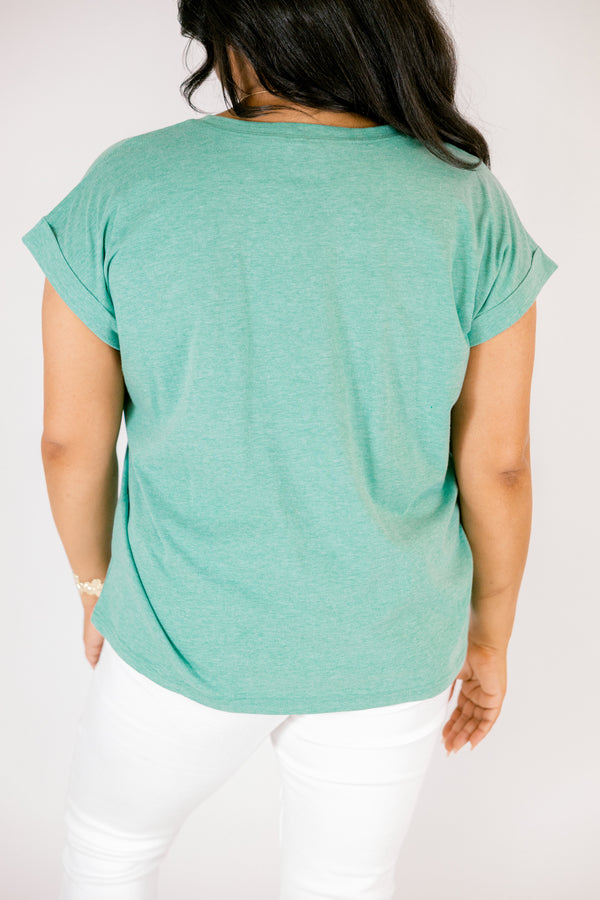 Plus Size heather kelly green crew neck cotton tee with cuffed short sleeves and white pants.