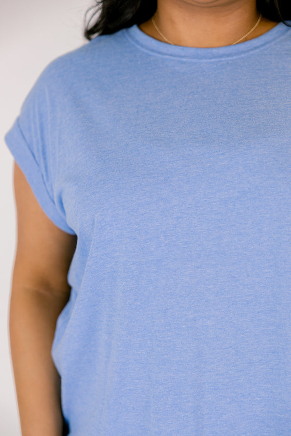 Plus Size heather ocean blue crew neck tee with cuffed short sleeves and white pants.