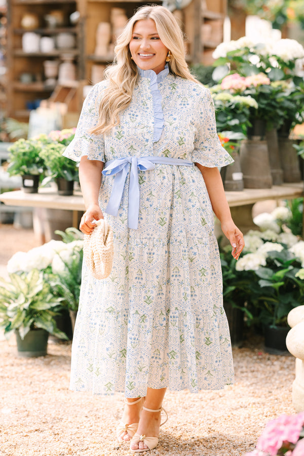 Chic Soul plus size clothing, blue maxi dress with shorts sleeves that flare out a blue multi floral pattern and a blue belt that ties into a bow that goes around the waist as blue ruffling details going along the neckline 