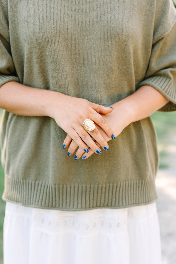 Close-up of a hand wearing the gold Saddle Creek coin ring