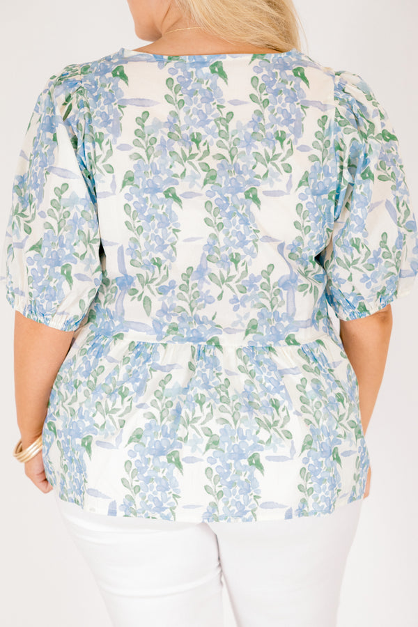 Chic Soul plus size clothing, white puff short sleeve babydoll top with light blue and green floral pattern and three blue bow ties down the middle of the top and cinching at the end of the sleeves