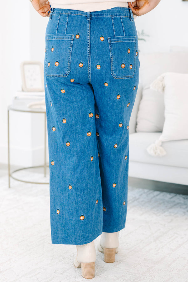 Plus size wide leg blue denim jeans with all-over pumpkin embroidery and a raw hem.