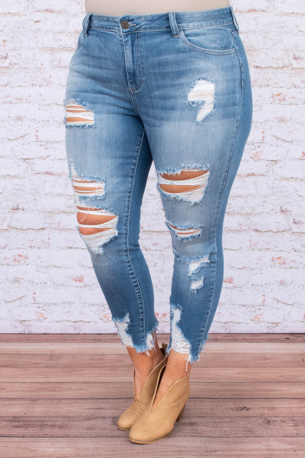 Plus Size medium wash skinny jeans with heavy distressing, ripped knees, and frayed hems.