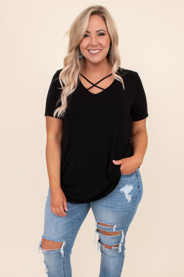 Plus Size black short sleeve top with a criss-cross V-neckline and distressed light wash jeans.