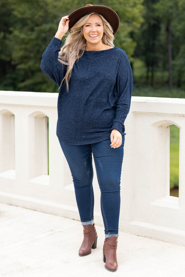 Plus Size navy blue long sleeve top with a boat neckline and relaxed fit paired with dark jeans.
