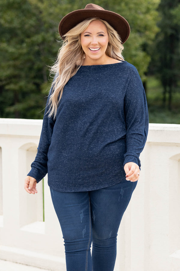 Plus Size navy blue long sleeve top with a boat neckline and relaxed fit paired with dark jeans.